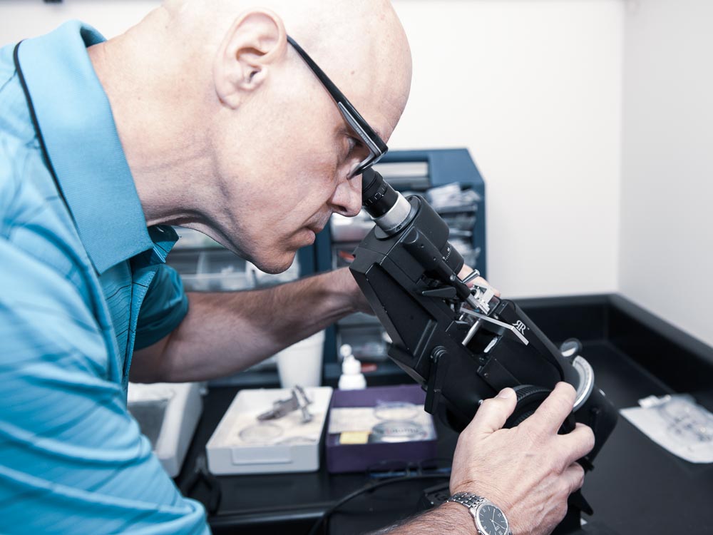 Optician Rhyne Maynard inspecting eyeglass lenses with a lensometer