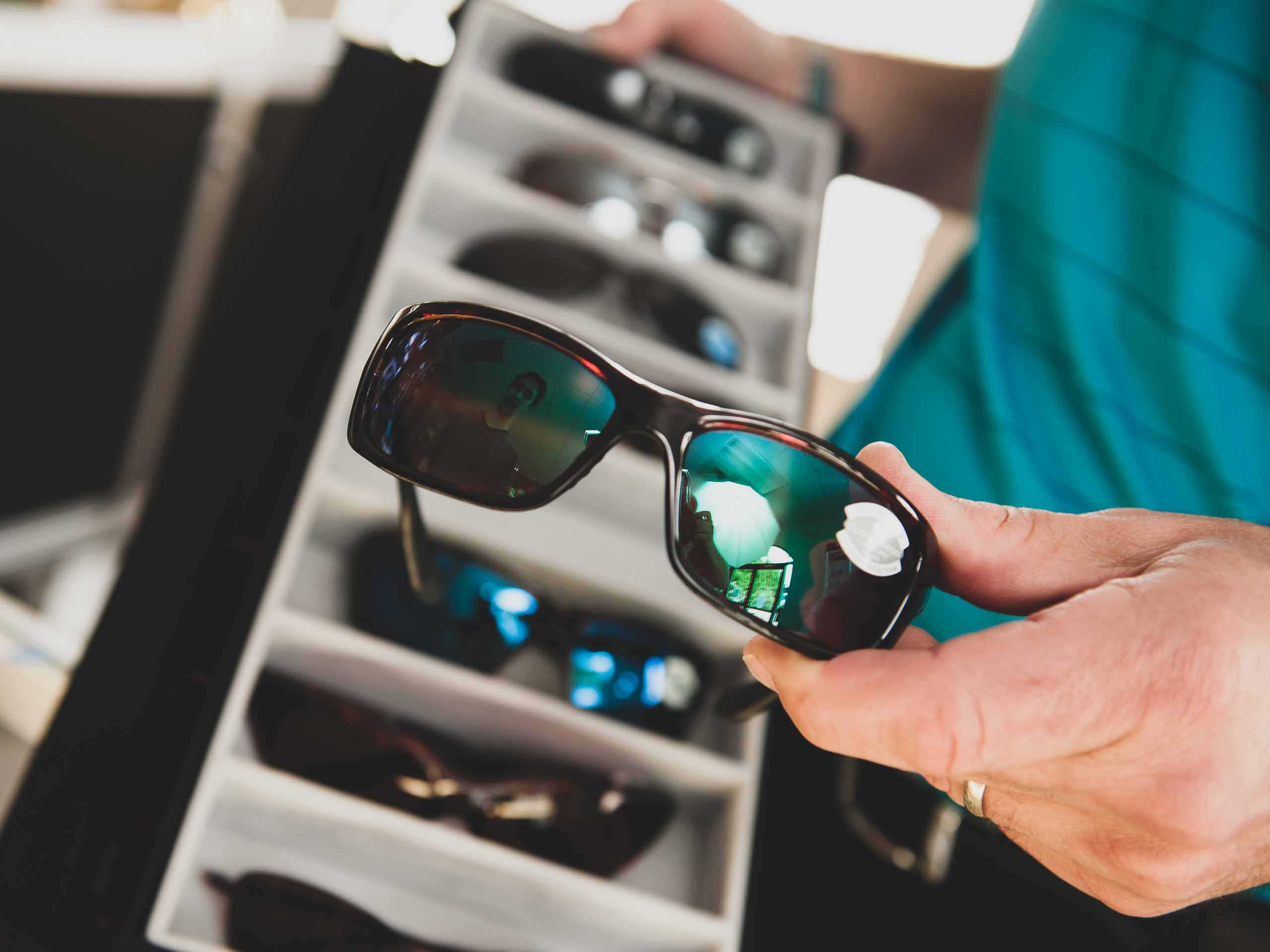 Optician Rhyne Maynard holding a pair of Costa Del Mar sunglasses